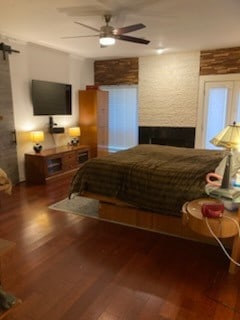 bedroom with wood finished floors, ceiling fan, and a barn door