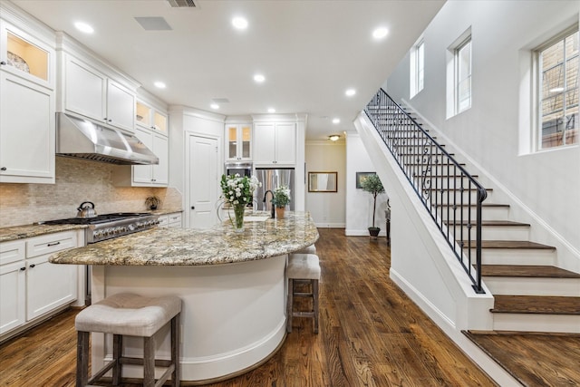 5021 Augusta St, Houston, TX 77007 - kitchen featuring white cabinets, backsplash, light stone counters, a breakfast bar, and under cabinet range hood