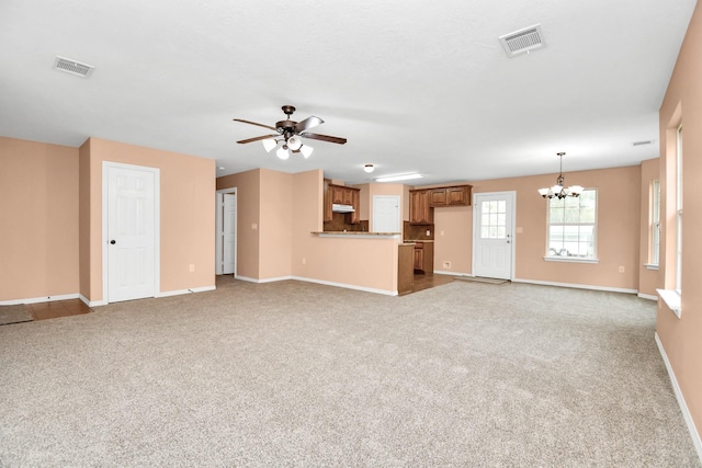 unfurnished living room featuring ceiling fan with notable chandelier, baseboards, visible vents, and carpet