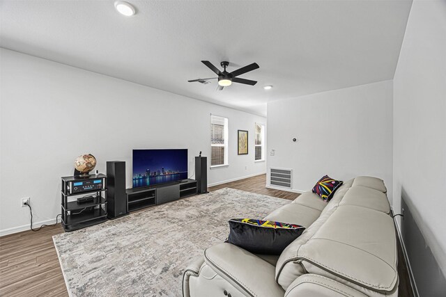 living area featuring wood finished floors, visible vents, baseboards, and ceiling fan