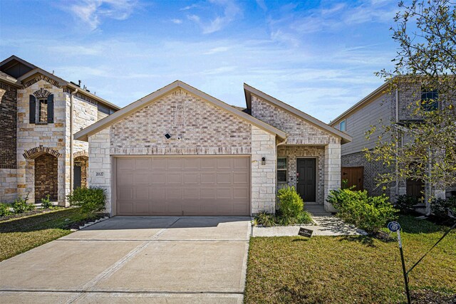 french country style house with an attached garage, driveway, stone siding, and a front yard