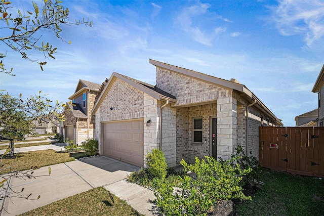 view of front of property featuring a gate, fence, concrete driveway, an attached garage, and stone siding