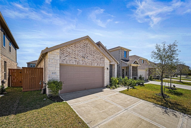 view of front of house featuring concrete driveway, a front lawn, stone siding, fence, and a garage