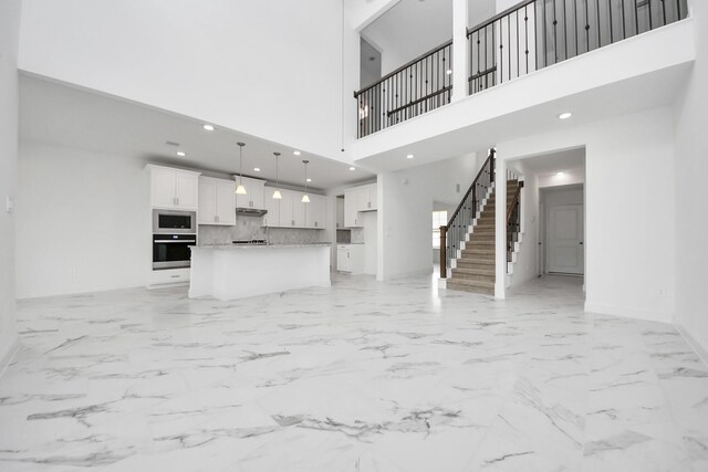 15607 Boulder Lake Ln, Conroe, TX 77302 - unfurnished living room featuring recessed lighting, baseboards, marble finish floor, stairs, and a towering ceiling