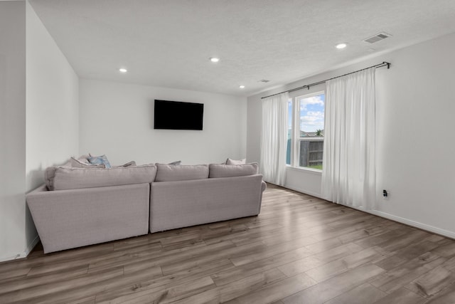 living area with baseboards, recessed lighting, wood finished floors, and visible vents