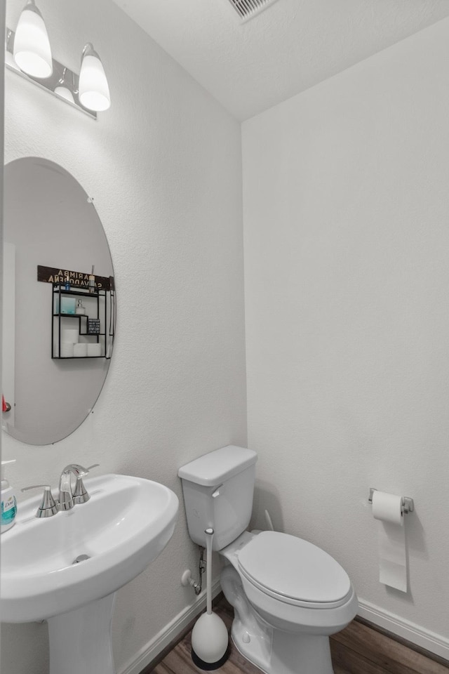 bathroom with a sink, baseboards, toilet, and wood finished floors