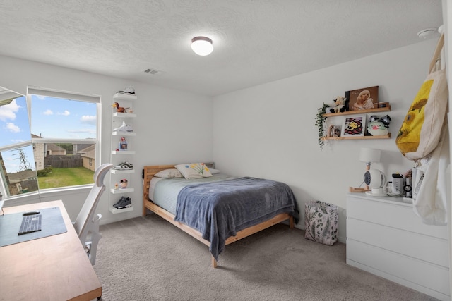 bedroom with a textured ceiling and light colored carpet