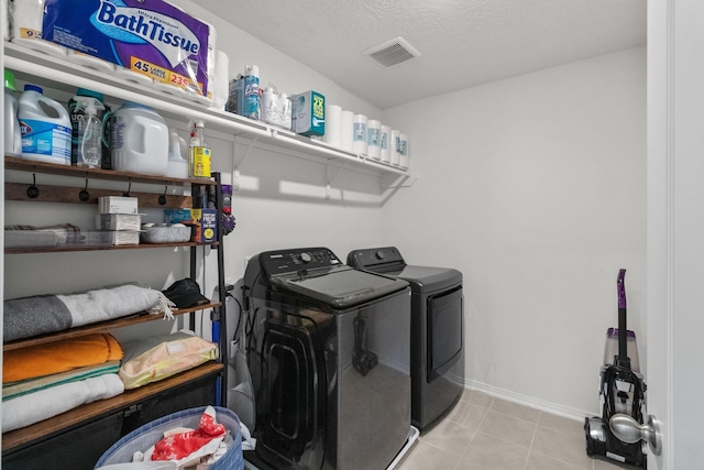 washroom with laundry area, visible vents, tile patterned flooring, baseboards, and washer and dryer