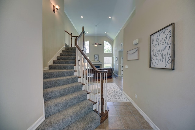 stairway featuring crown molding, ceiling fan, baseboards, recessed lighting, and a fireplace