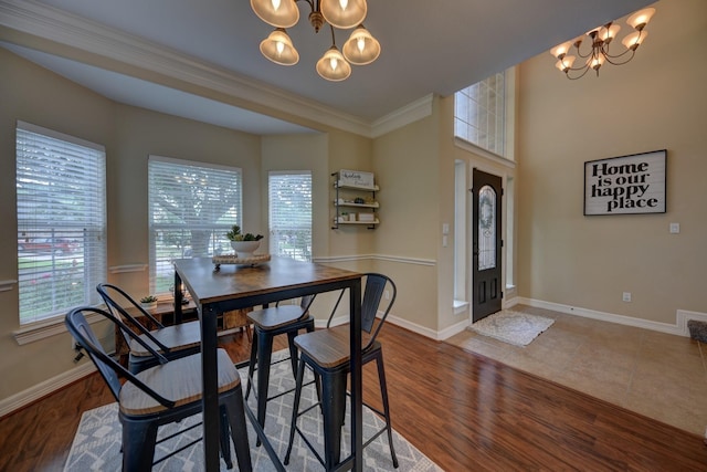 dining room featuring crown molding, a notable chandelier, wood finished floors, and baseboards