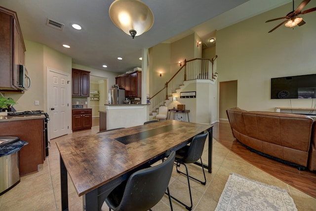 dining area featuring light tile patterned floors, a ceiling fan, visible vents, and stairs