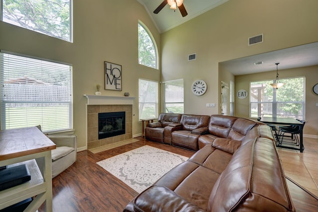 living area with ceiling fan, visible vents, baseboards, a fireplace, and high vaulted ceiling