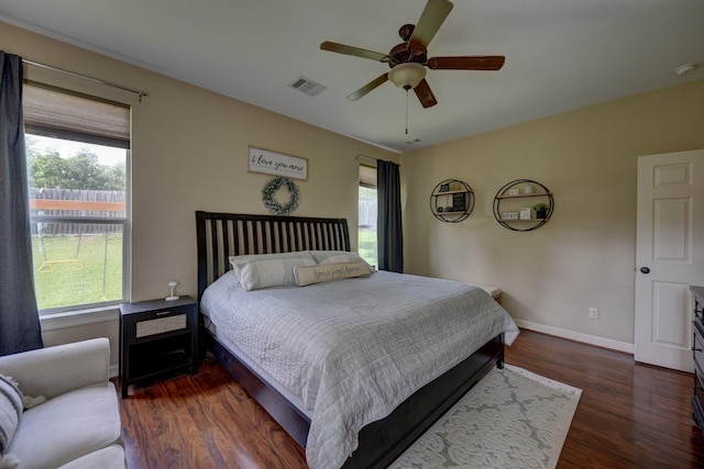 bedroom with multiple windows, baseboards, dark wood-style flooring, and visible vents