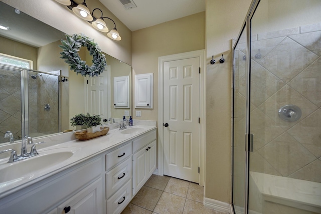 bathroom with a stall shower, double vanity, a sink, and tile patterned floors