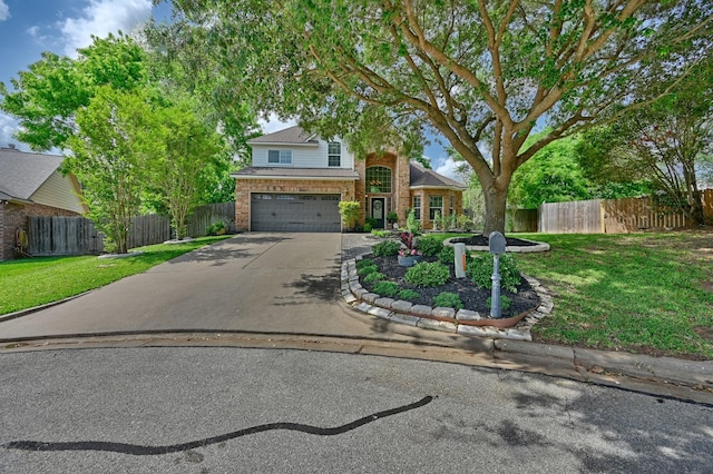 view of front facade with brick siding, fence, driveway, a front lawn, and an attached garage