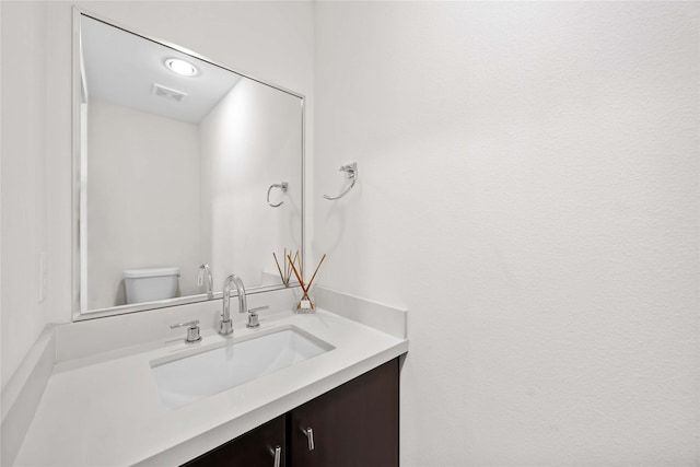 bathroom featuring toilet, vanity, and visible vents