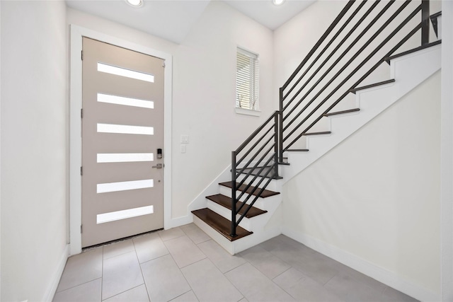 foyer featuring baseboards, light tile patterned flooring, stairs, and recessed lighting