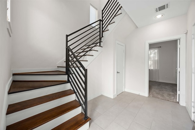 staircase with carpet floors, visible vents, tile patterned floors, and baseboards