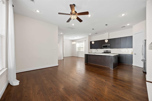 kitchen with stainless steel appliances, light countertops, visible vents, a kitchen island with sink, and open floor plan