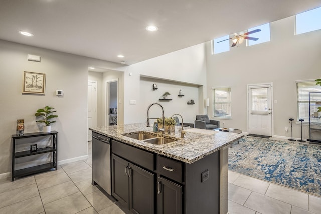 kitchen featuring a sink, open floor plan, light stone counters, dishwasher, and an island with sink