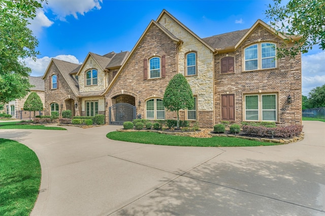 21411 Fairhaven Creek Dr, Cypress, TX 77433 - french provincial home featuring brick siding, a gate, curved driveway, and stone siding