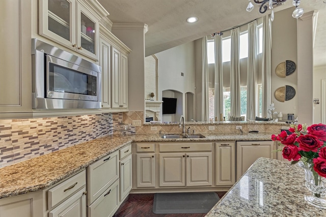 21411 Fairhaven Creek Dr, Cypress, TX 77433 - kitchen featuring a sink, stainless steel microwave, cream cabinetry, light stone counters, and tasteful backsplash