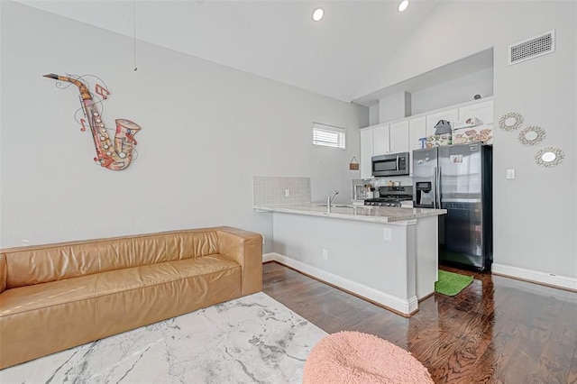 kitchen with stainless steel appliances, white cabinetry, a peninsula, dark wood-style flooring, and visible vents
