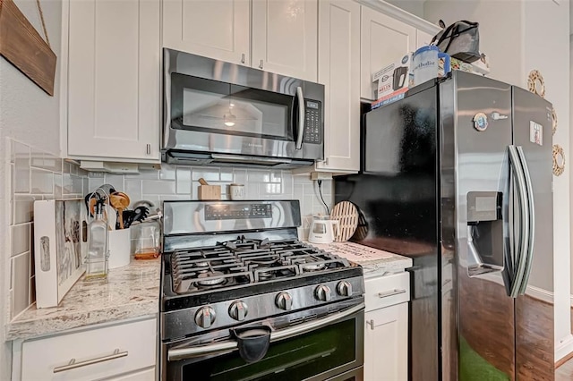 kitchen featuring white cabinets, light stone countertops, appliances with stainless steel finishes, and decorative backsplash