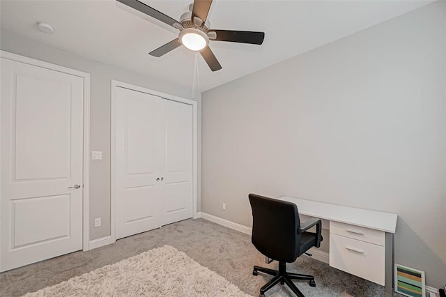 carpeted office with a ceiling fan and baseboards