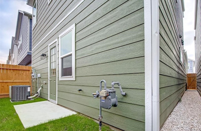 view of side of home featuring fence, central air condition unit, and a patio