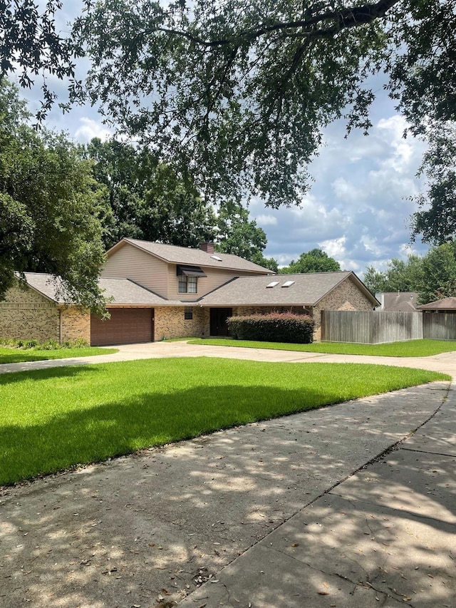 9948 Twin Shores Dr, Willis, TX 77318 - view of front of home with concrete driveway, fence, a front yard, and a garage