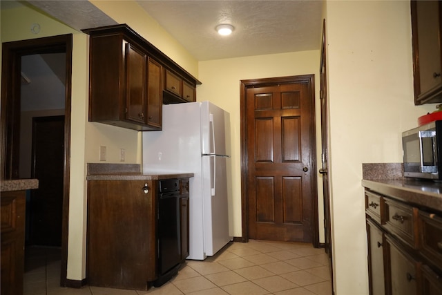 9948 Twin Shores Dr, Willis, TX 77318 - kitchen featuring freestanding refrigerator, stainless steel microwave, dark countertops, and light tile patterned floors