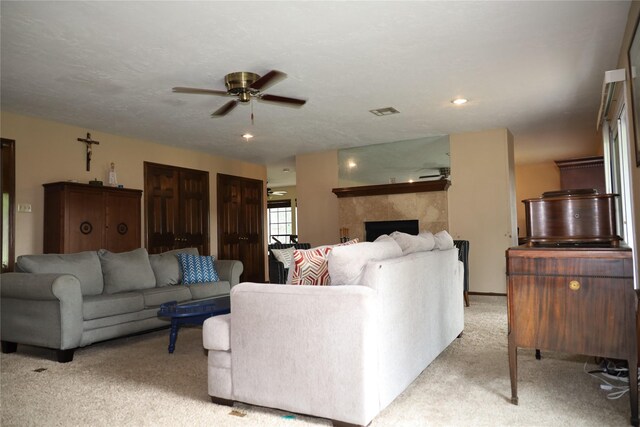 9948 Twin Shores Dr, Willis, TX 77318 - living room featuring a ceiling fan, visible vents, light carpet, and a fireplace