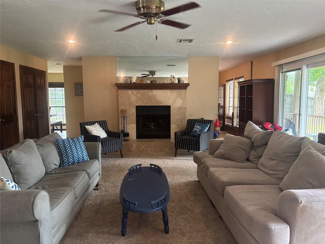 9948 Twin Shores Dr, Willis, TX 77318 - carpeted living room featuring a tiled fireplace, ceiling fan, and visible vents