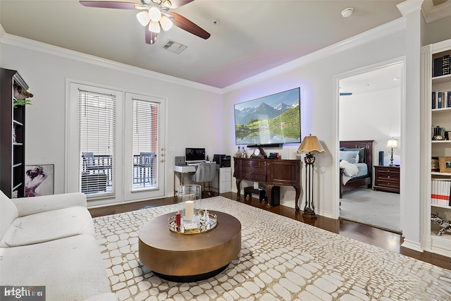 living area featuring wood finished floors, visible vents, ceiling fan, and ornamental molding