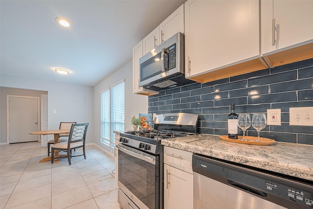 7730 Maple Tree Dr, Houston, TX 77088 - kitchen with stainless steel appliances, light tile patterned floors, tasteful backsplash, and white cabinets