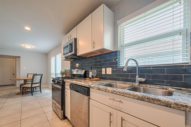 7730 Maple Tree Dr, Houston, TX 77088 - kitchen featuring appliances with stainless steel finishes, a sink, light tile patterned flooring, decorative backsplash, and white cabinets