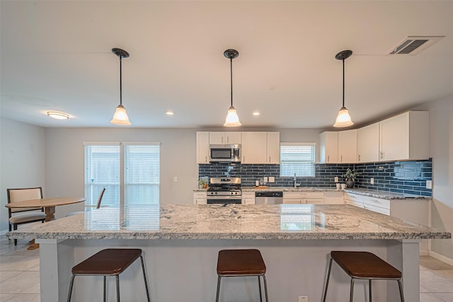 7730 Maple Tree Dr, Houston, TX 77088 - kitchen featuring appliances with stainless steel finishes, decorative backsplash, a kitchen bar, white cabinetry, and baseboards