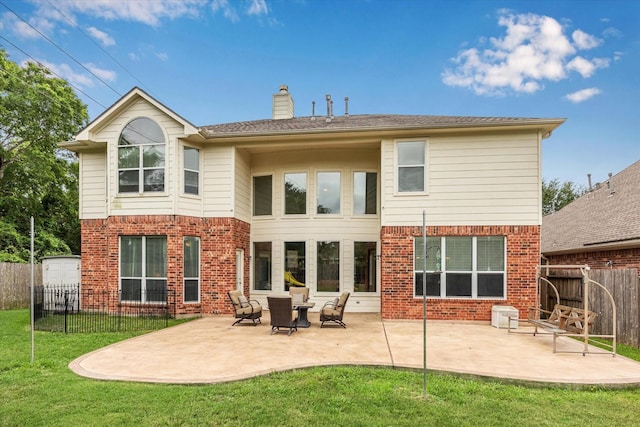 back of property featuring a fenced backyard, a chimney, brick siding, a patio area, and a yard