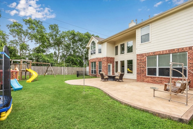 rear view of house featuring brick siding, a fenced backyard, a patio, and a playground