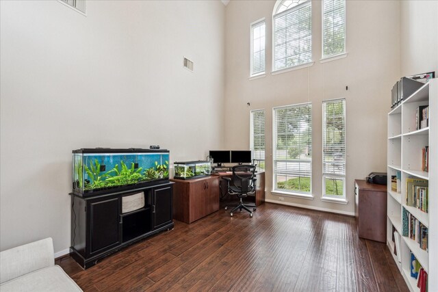 office with a towering ceiling, wood finished floors, and visible vents