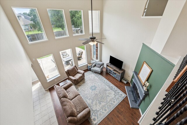 living area featuring a ceiling fan, a towering ceiling, and wood finished floors