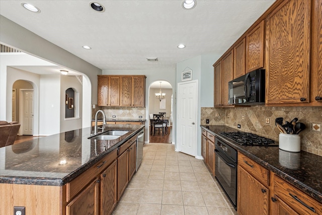 kitchen featuring brown cabinetry, a sink, light tile patterned flooring, arched walkways, and black appliances