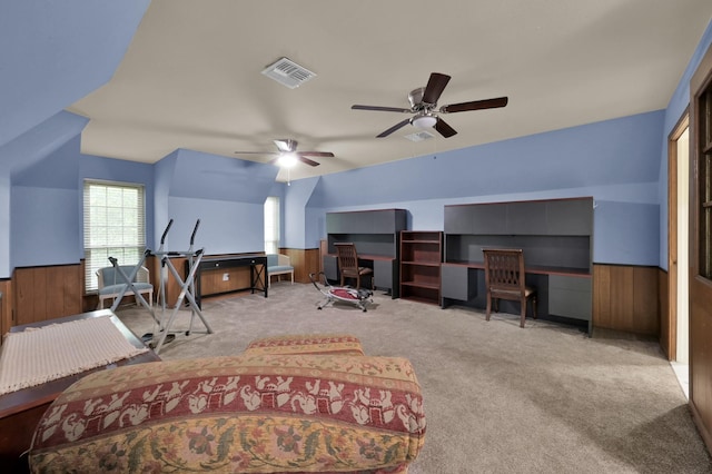 carpeted bedroom with visible vents, a ceiling fan, a wainscoted wall, and wooden walls