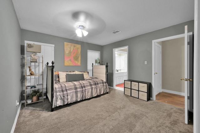 carpeted bedroom with ensuite bathroom, a ceiling fan, visible vents, and baseboards