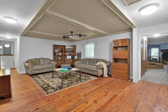 living room with beamed ceiling, plenty of natural light, baseboards, and light wood-style floors