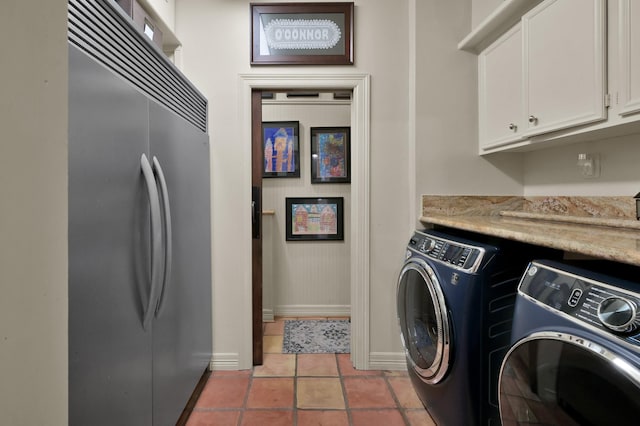 laundry area with light tile patterned flooring, separate washer and dryer, cabinet space, and baseboards