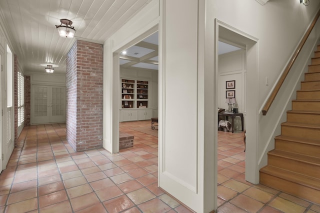 hallway with light tile patterned floors, wooden ceiling, built in shelves, and stairs