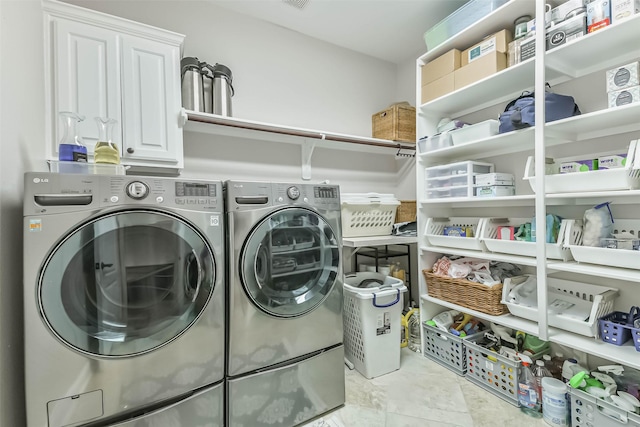 clothes washing area featuring cabinet space and washer and clothes dryer