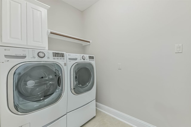 washroom featuring light tile patterned floors, separate washer and dryer, cabinet space, and baseboards